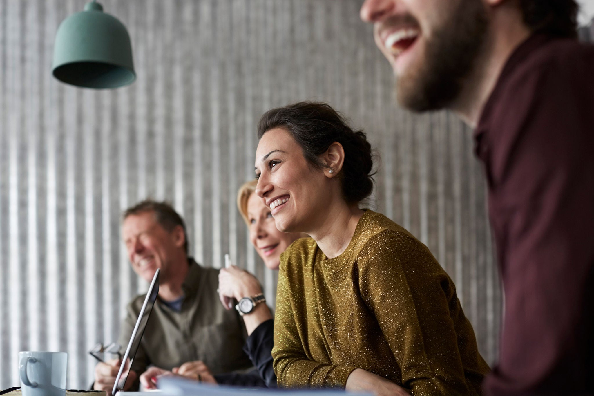 Cheerful creative business colleagues sitting at conference table while looking away in board room